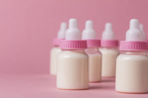 Biberon pieno di latte su uno sfondo rosa