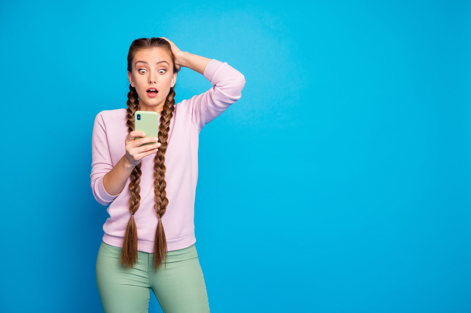 Ritratto di ragazza frustrata impressionata con lunghe trecce ottenere social media blog post commento guardare cellulare smartphone.