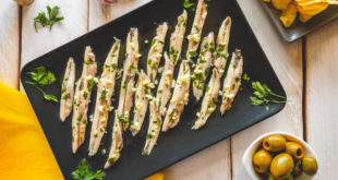 alici o acciughe marinate su un piatto nero rettangolare con prezzemolo e aglio