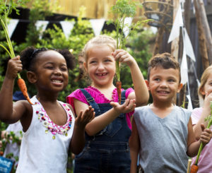 Un gruppo di bambini è in un giardino carote orti
