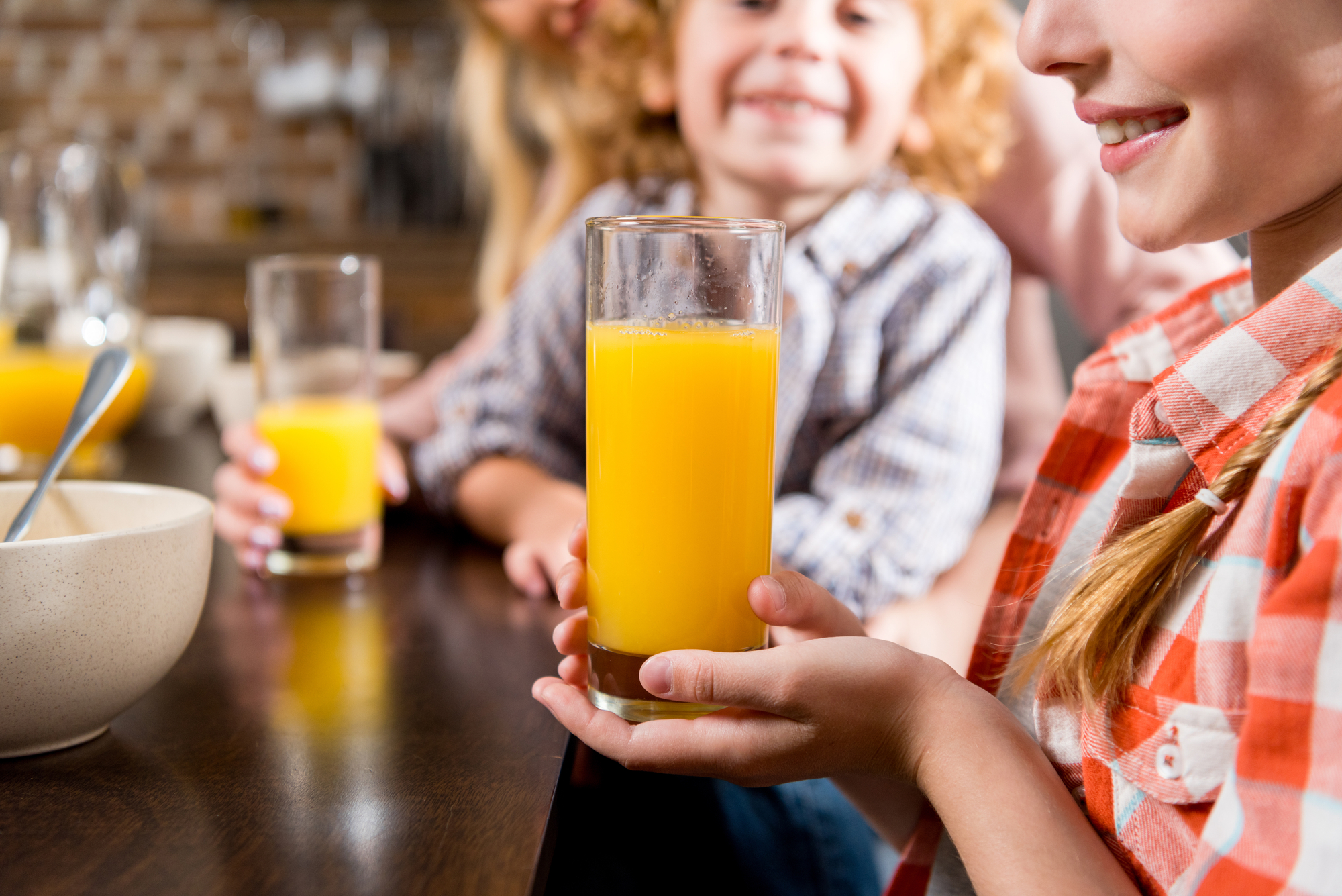 Bambini con bicchieri di succo di frutta a colazione