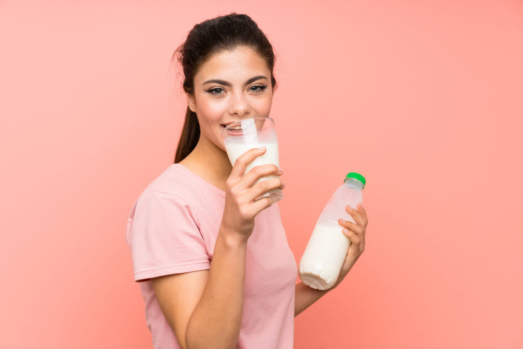 Ragazza dell'adolescente che beve latte della prima colazione animali clonati 