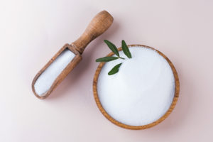 Dolcificante naturale eritritolo o stevia in una ciotola e un cucchiaio di legno