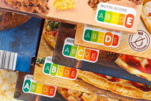 Nutri-Score da A ad E su diverse confezioni di pizza surgelata sovrapposte in scala