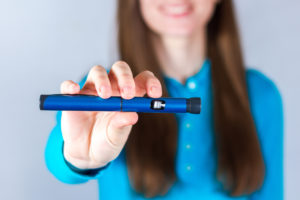 Donna che mostra penna con farmaco per il diabete o insulina