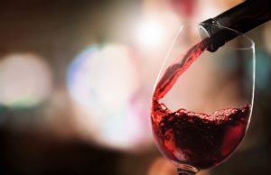 Vino rosso versato in un calice da una bottiglia