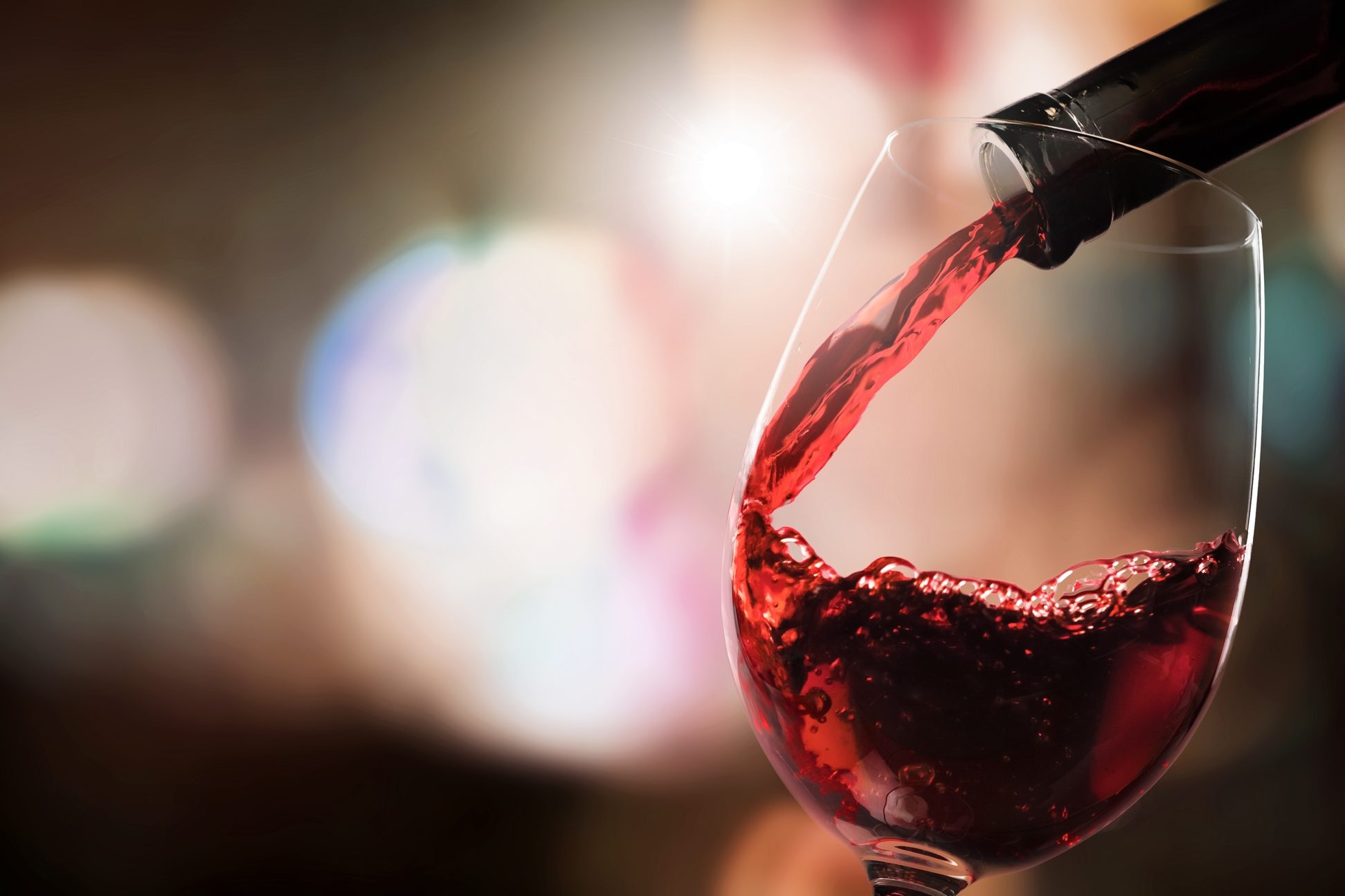 Vino rosso versato in un calice da una bottiglia