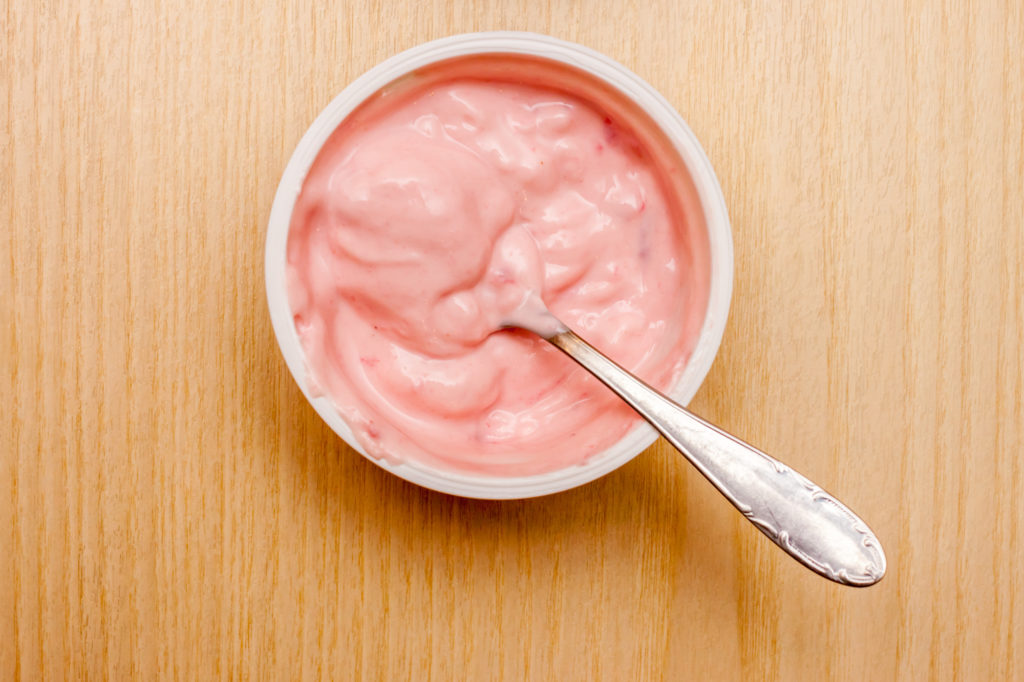 yogurt rosa alla fragola sul tavolo vista dall'alto latticini latte fermenti colazione plastica