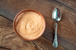 Ciotola di salsa accanto a un cucchiaio su tavolo di legno