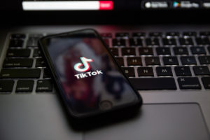 Smartphone con il logo di TikTok appoggiato sulla tastiera di un computer portatile o laptop