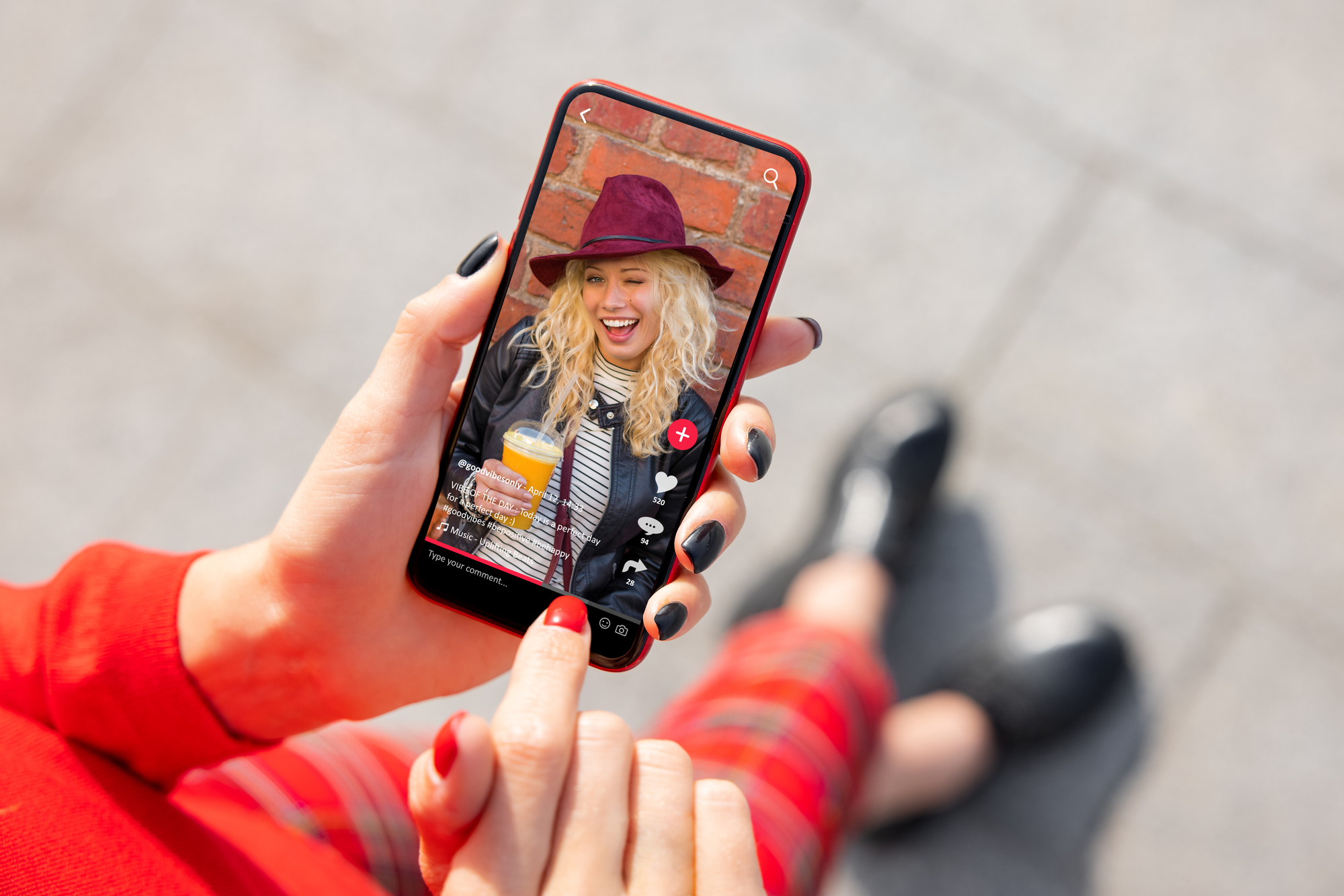 Ragazza tiene in mano smartphone con TikTok aperto su un video di una ragazza con in mano una bibita