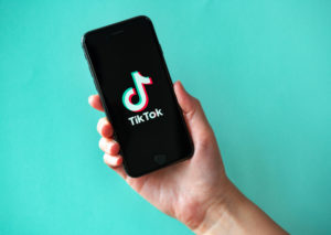 Mano tiene smartphone o iPhone con lo go di TikTok; concept: social media, influencer
