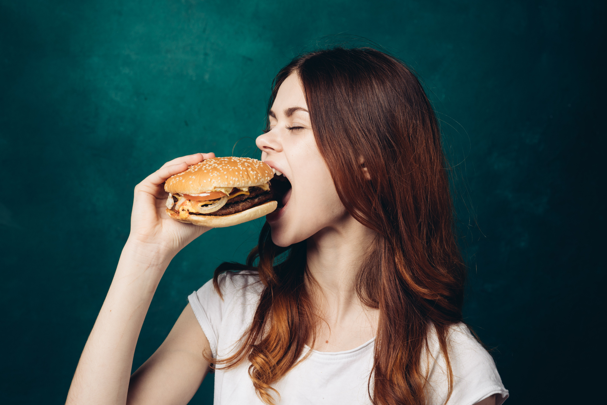 Ragazza mangia un hamburger: concept: junk food, ultra-trasformati, ultra processati, proteine