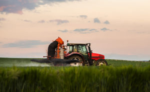 Trattore spruzza pesticidi o fertilizzanti su un campo; concept: glifosato, agricoltura