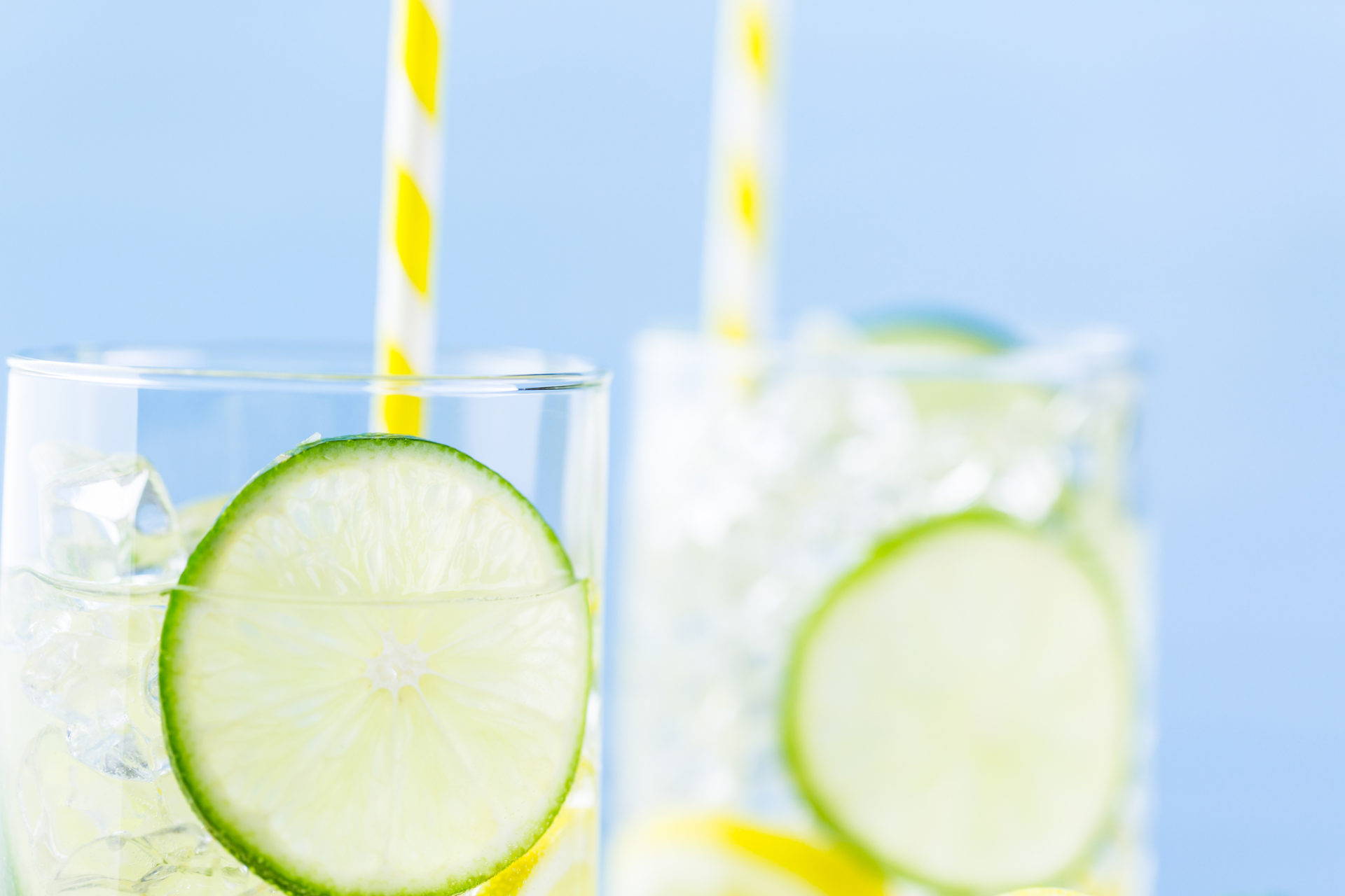Due bicchieri di acqua aromatizzata con lime, limone e ghiaccio con cannucce