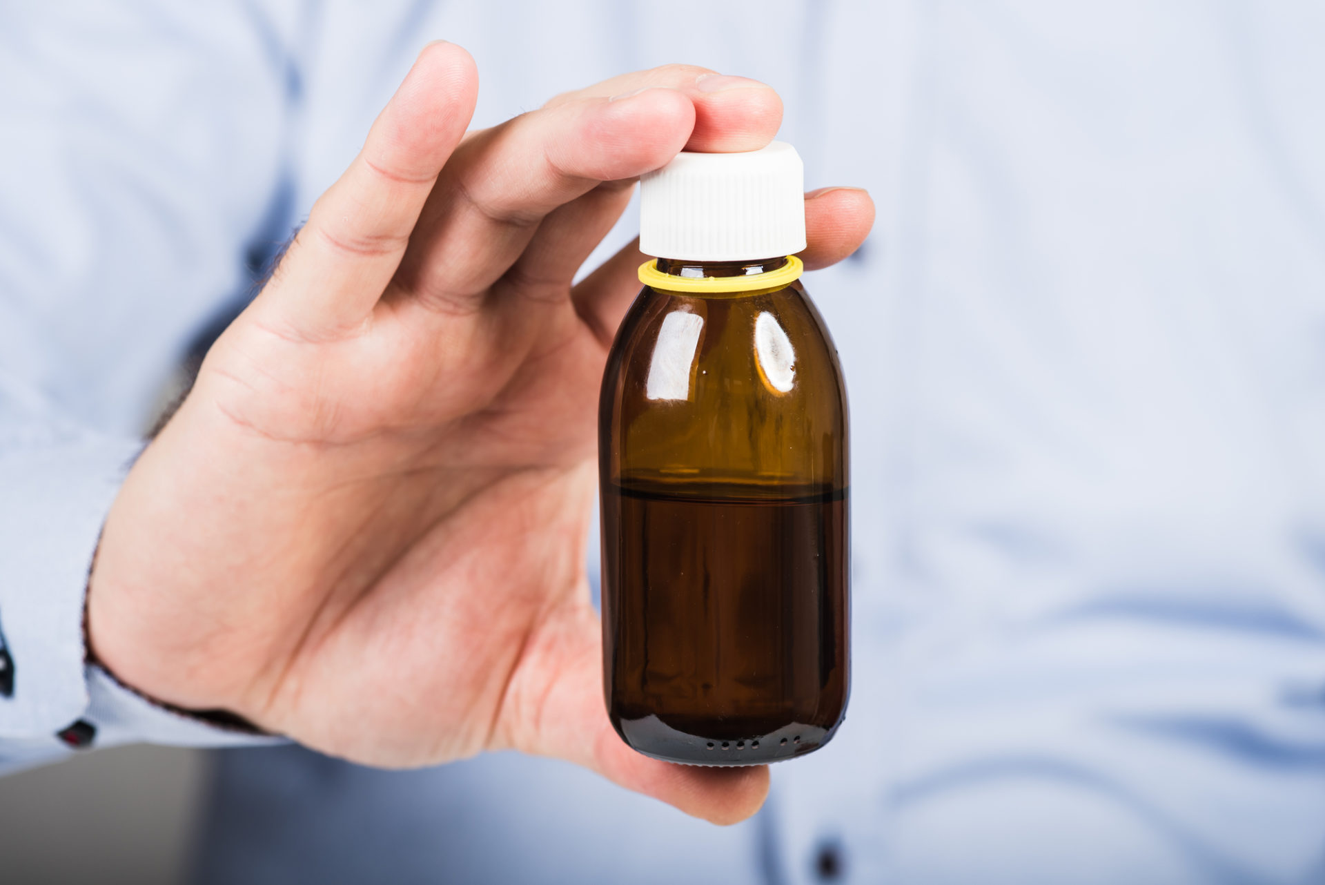 Un uomo tiene in mano un flaconcino di farmaco, sciroppo o integratore