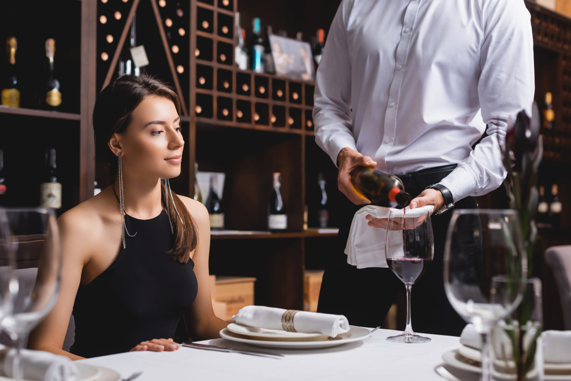 Sommelier versa vino rosso a una donna in un ristorante