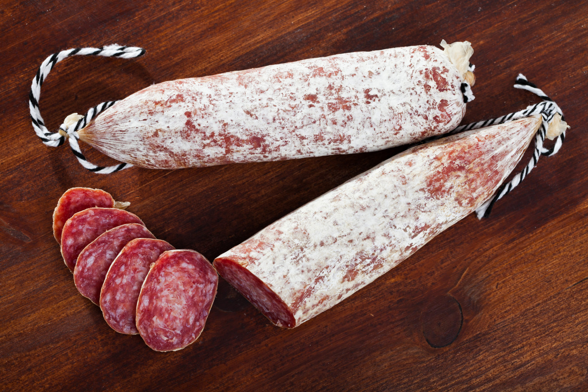 Salame intero e affettato su un tavolo di legno