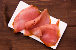 Fette di tonno affumicato su un piattino rettangolare su tavolo di legno