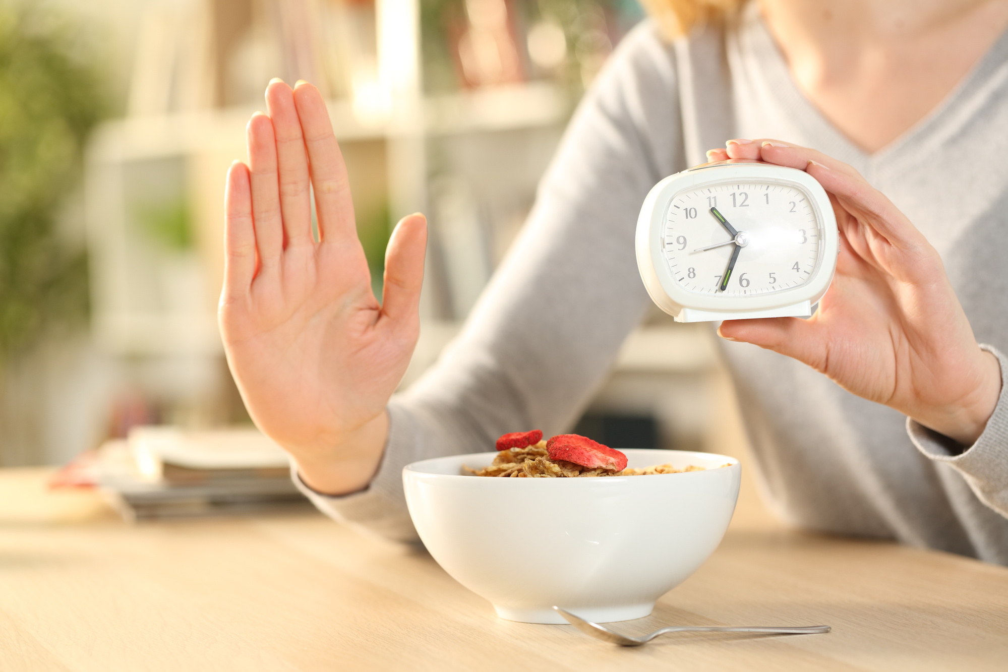 Primo piano di mani di donna a digiuno intermittente facendo segno di stop in attesa prima di mangiare ciotola di cereali su un tavolo a casa dieta