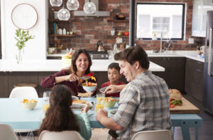 Famiglia che si gode il pasto intorno al tavolo di casa insieme pranzo cena