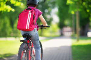 Bambino in bicicletta con zaino in spalla