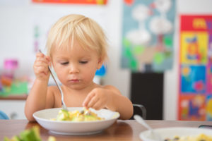 Un dolce bambino, che mangia gli spaghetti a casa, fa confusione e si diverte a giocare con loro alimentazione bambini verdure zuccheri