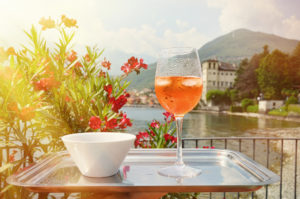 Calice di spritz e ciotola di stuzzichini su vassoio in una terrazza sul lago di Como; concept: cocktail, aperitivo