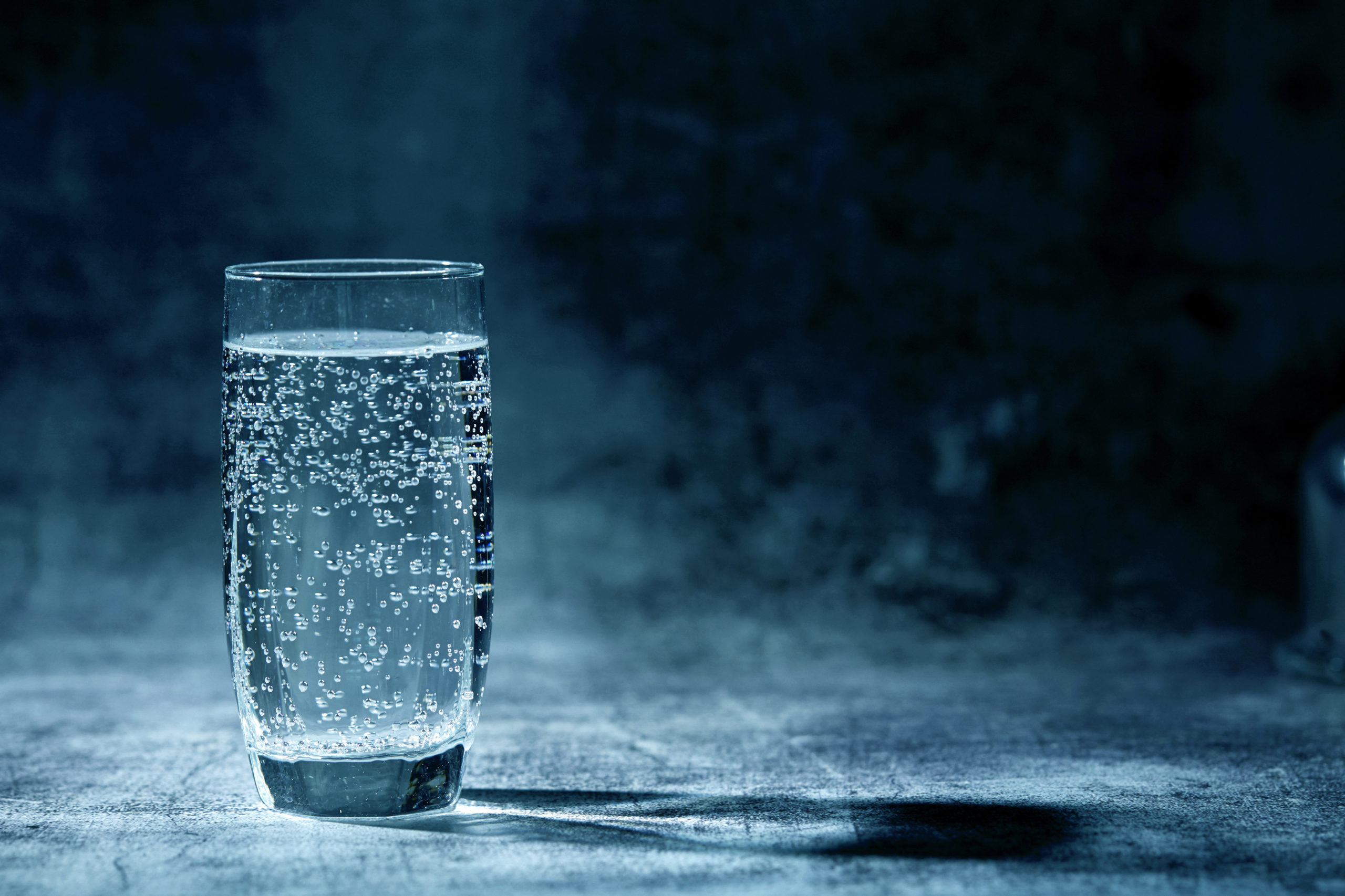 Bicchiere di acqua frizzante su sfondo grigio acqua minerale bicchiere di vetro