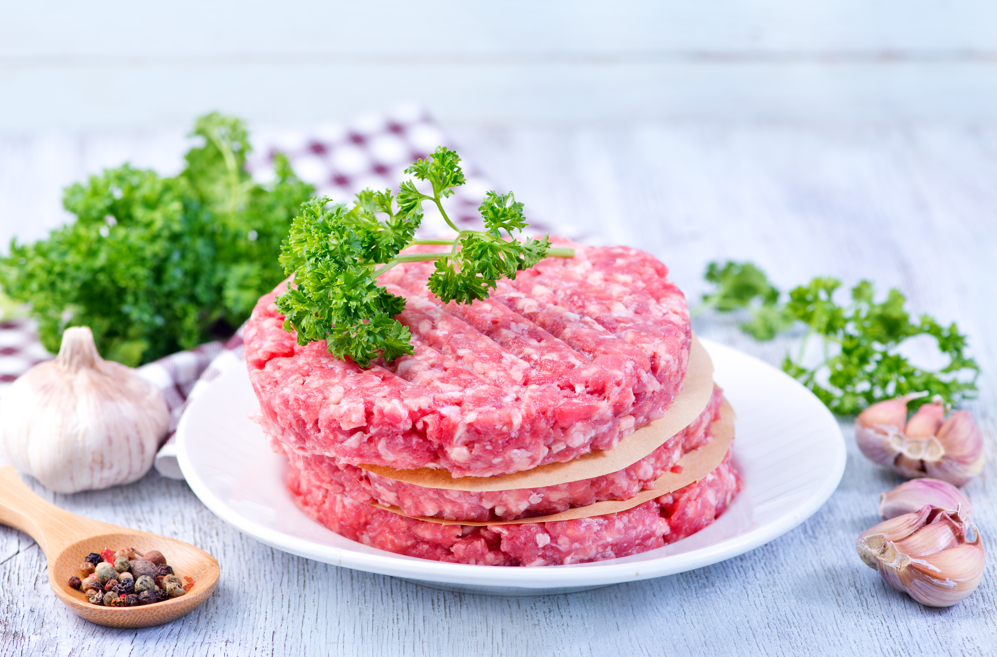 Burger di manzo o maiale crudi impilati con prezzemolo, aglio e pepe; concept: carne cruda