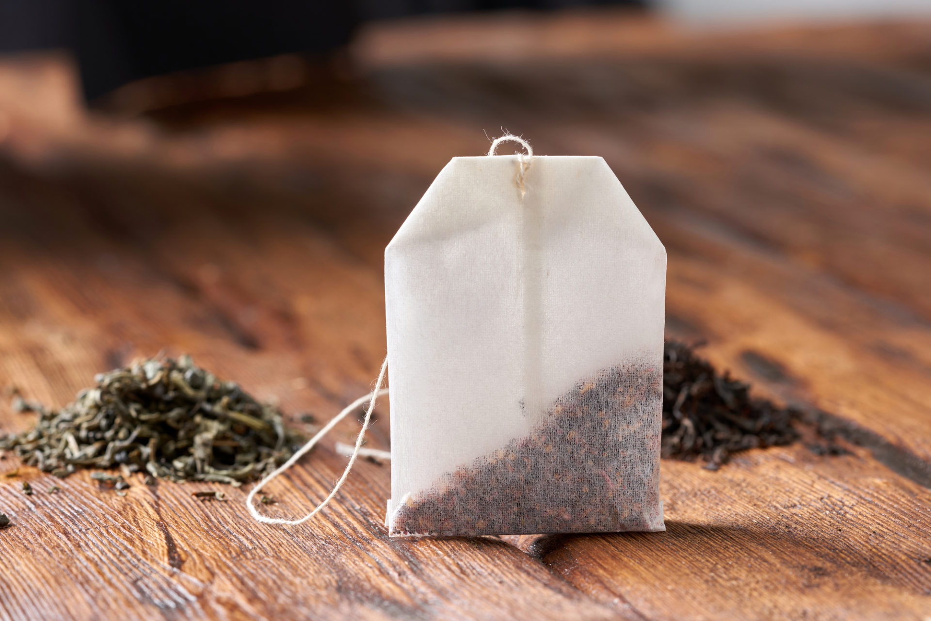 Bustina di tè o infuso con foglie di tè verde e tè nero sullo sfondo