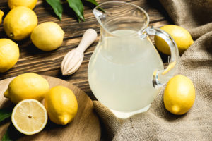Caraffa di limonata circondata da limoni su un tavolo di legno