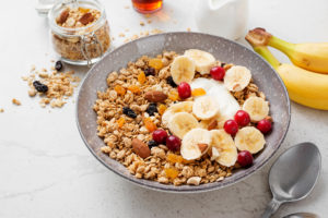 Ciotola di muesli o granola con frutta fresca, frutta secca e frutta essiccata; concept: colazione