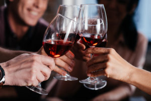 Gruppo di amici brinda con calici di vino rosso