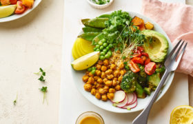 Piatto vegano con ceci, piselli, taccole, avocado, rapanelli, broccoli, pomodorini, zucca e germogli; concept: dieta vegana, plant based, legumi