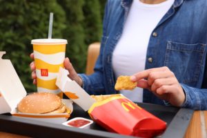 Donna mangia un menu di McDonald's: panino con hamburger, nuggets e bibita