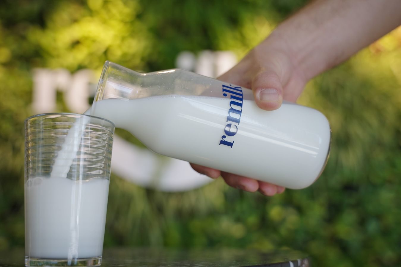 Latte da fermentazione versato da una bottiglia con la scritta Remilk; concept: latte sintetico; fonte Remilk