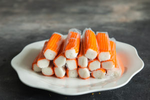 Surimi industriale ancora avvolto nella plastica su un piatto bianco