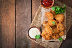 Nuggets vegetali o di pollo su un tagliere con salse e prezzemolo