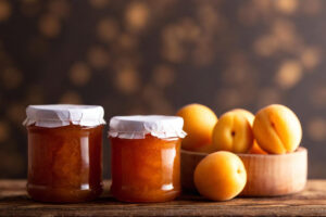 Due vasetti di marmellata di albicocche, accanto ad albicocche sul tavolo; concept: shrinkflation