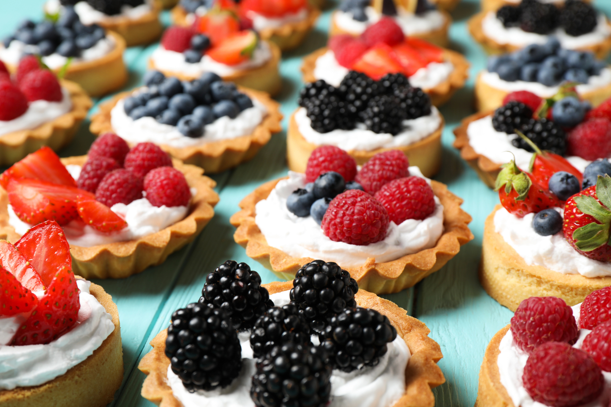 Pasticcini o tartellette ai frutti di bosco con panna; concept: dolci, pasticceria