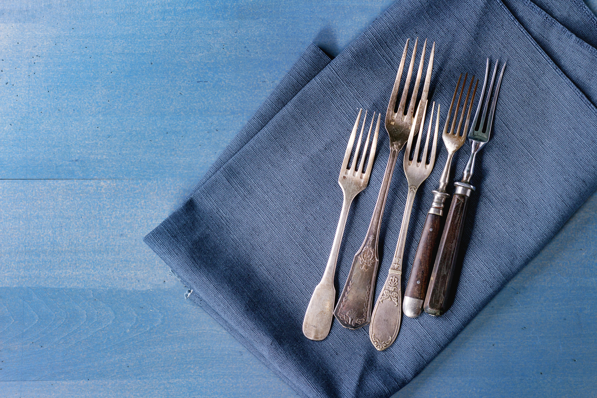 Forchette vintage o antiche su un tovagliolo blu; concept: posate