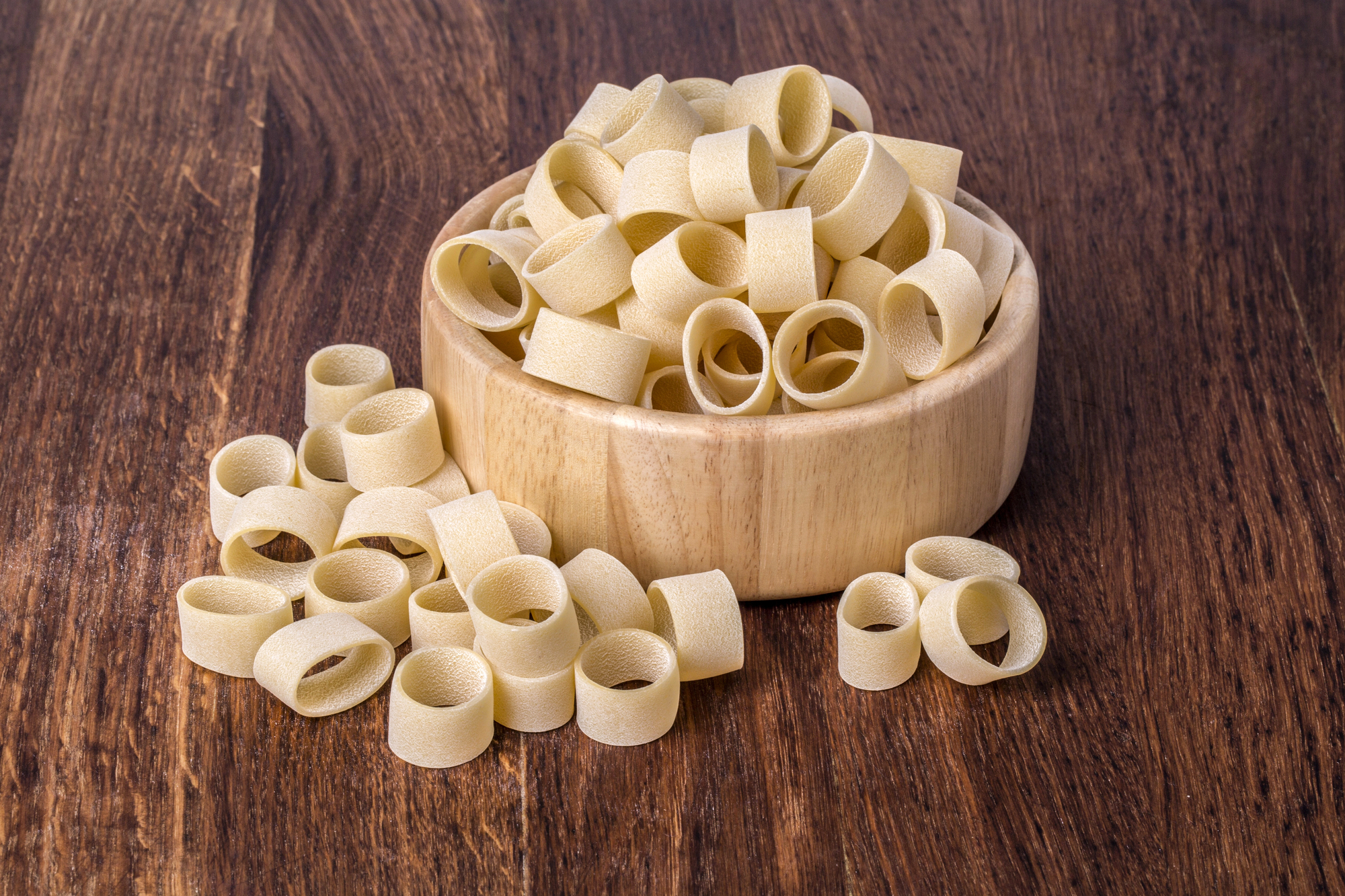 Ciotola di legno piena di pasta formato calamarata
