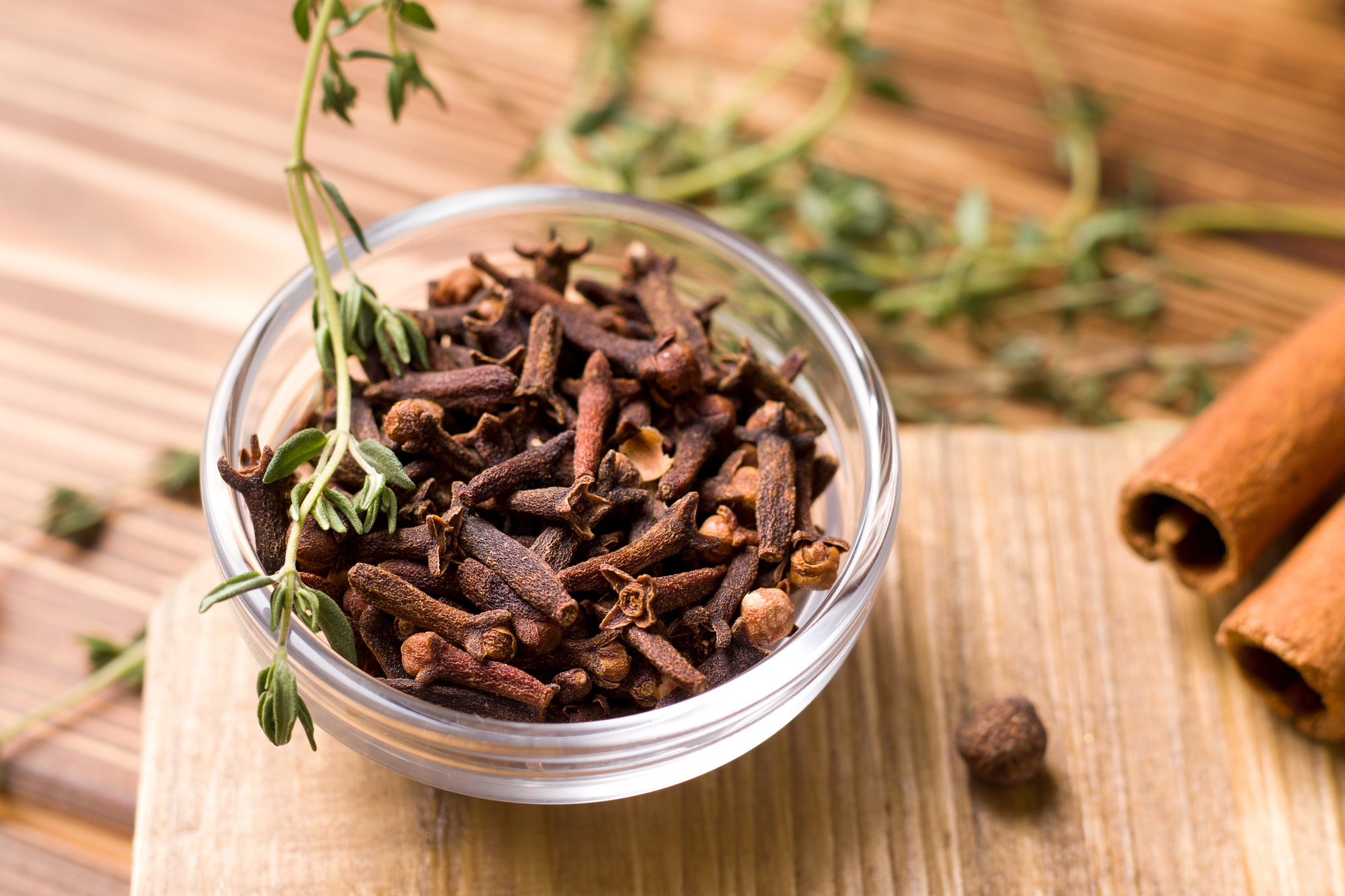 Ciotolina di chiodi di garofano, attorno erbe aromatiche e cannella; concept: spezie