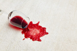 Bicchiere di vino rosso rovesciato su una tovaglia chiara; concept: alcol, bevande alcoliche