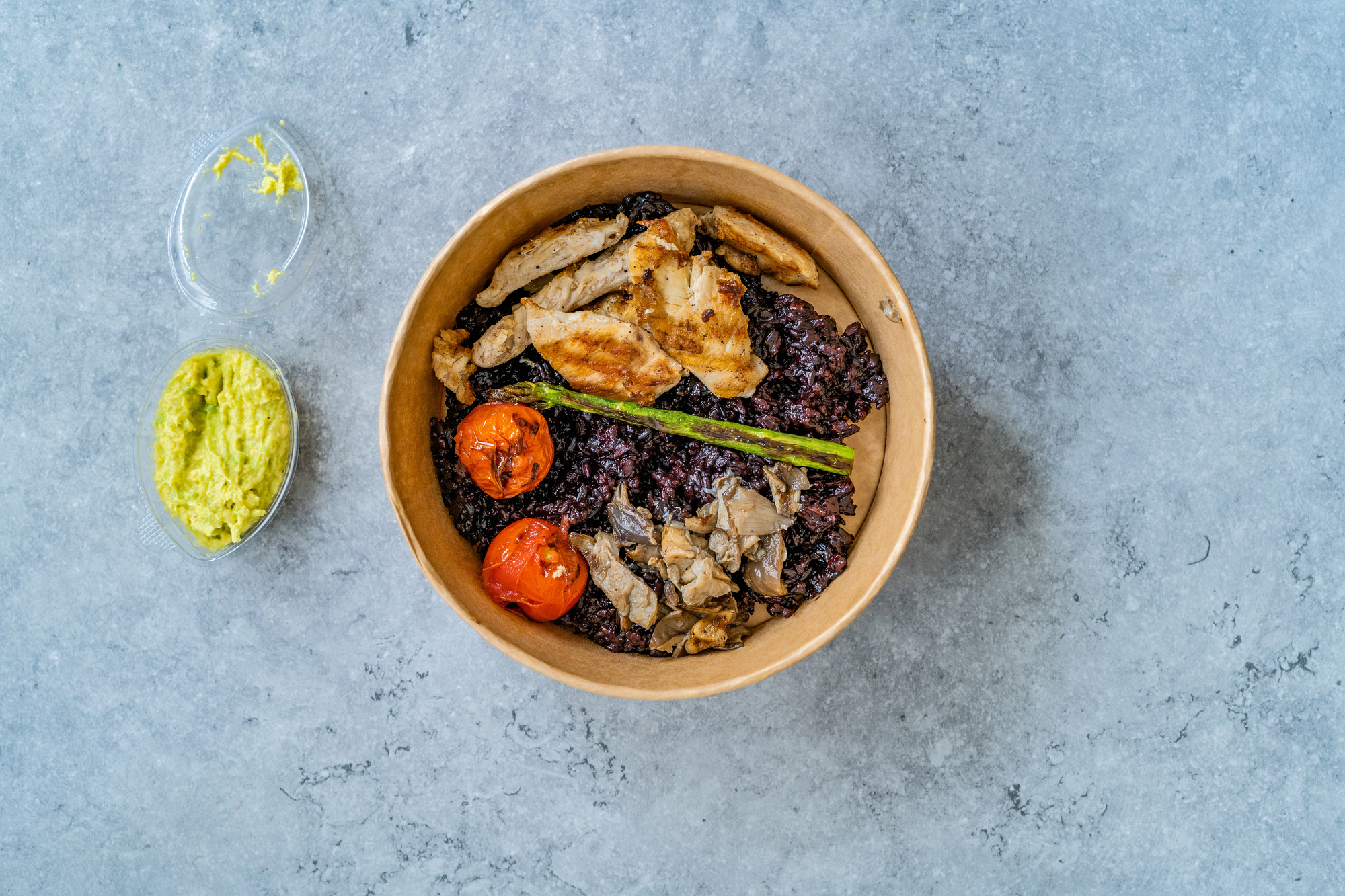 Bowl di riso nero, con pollo arrosto, funghi e pomodori, con ciotolina di guacamole; concept: insalata di riso, poké