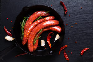 Salsicce crude piccanti in una padella di ghisa con aglio peperoncino e rosmarino; concept: salsiccia