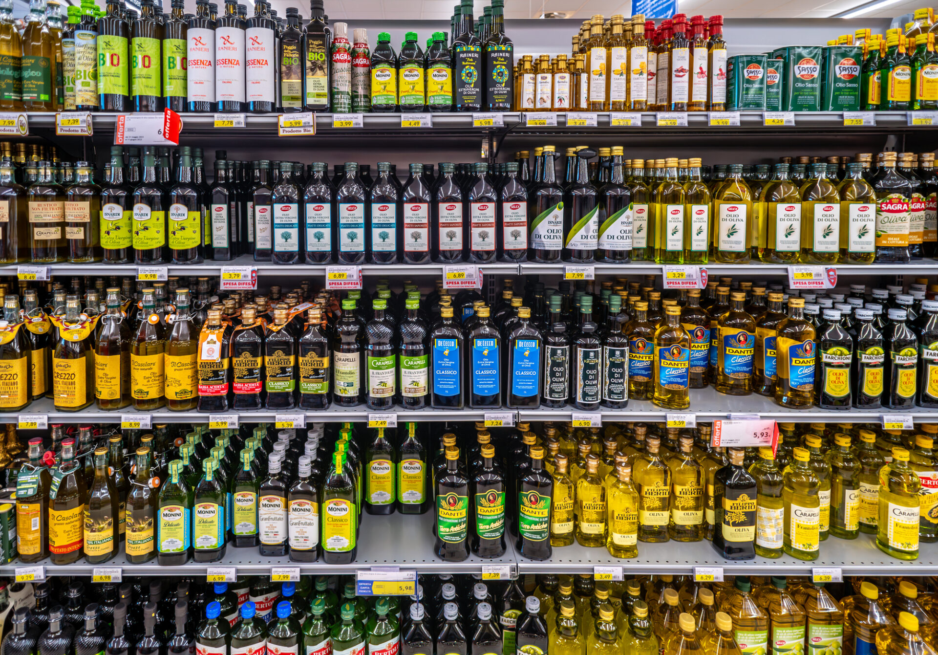 Scaffale dl supermercato carico di bottiglie di olio extravergine di oliva