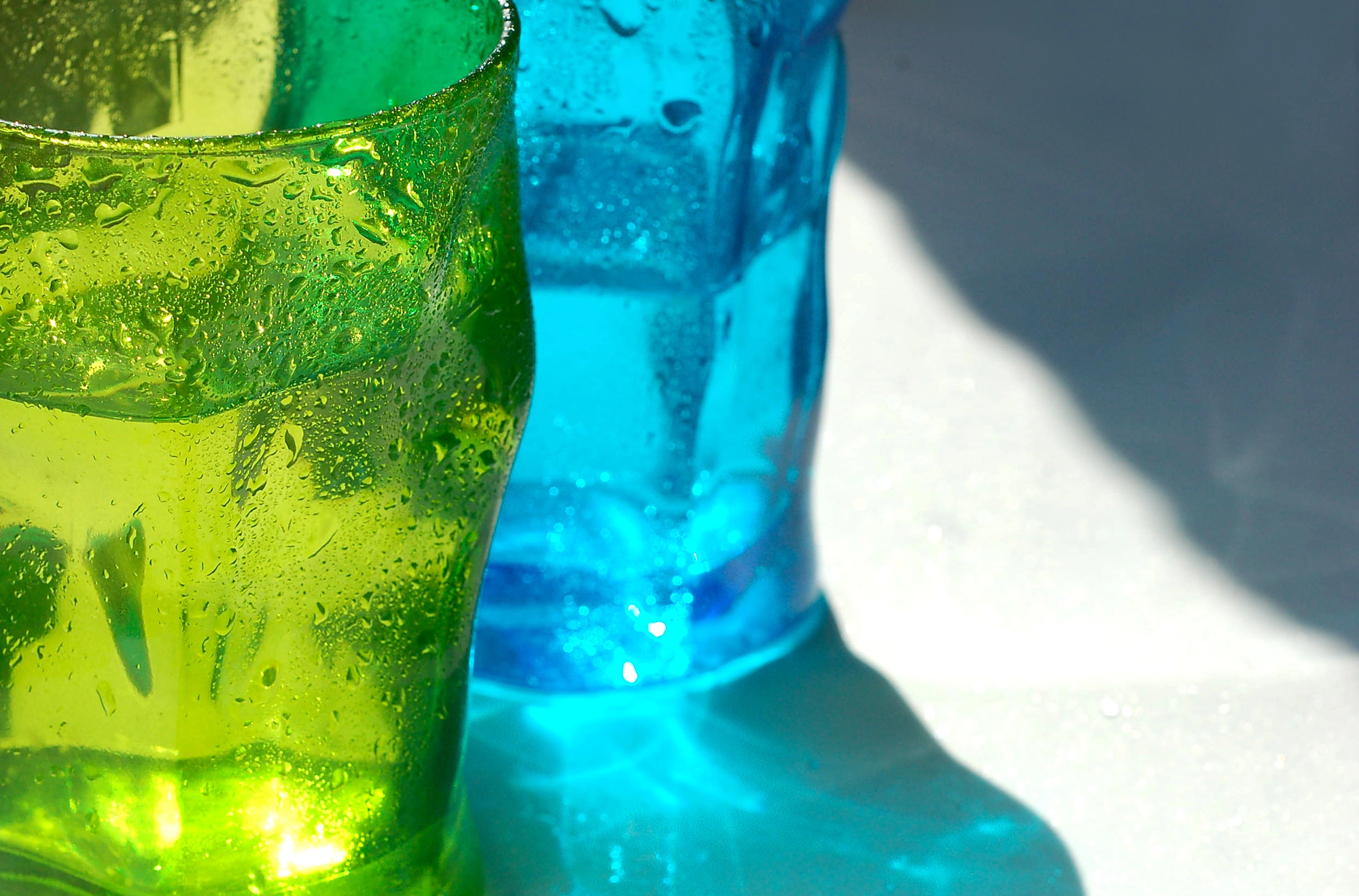 Due bicchieri di vetro colorato, uno verde e uno azzurro, pieni d'acqua