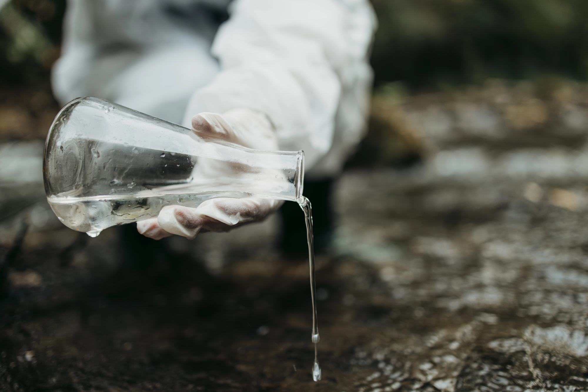 Scienziato preleva acqua con una beuta da un fiume